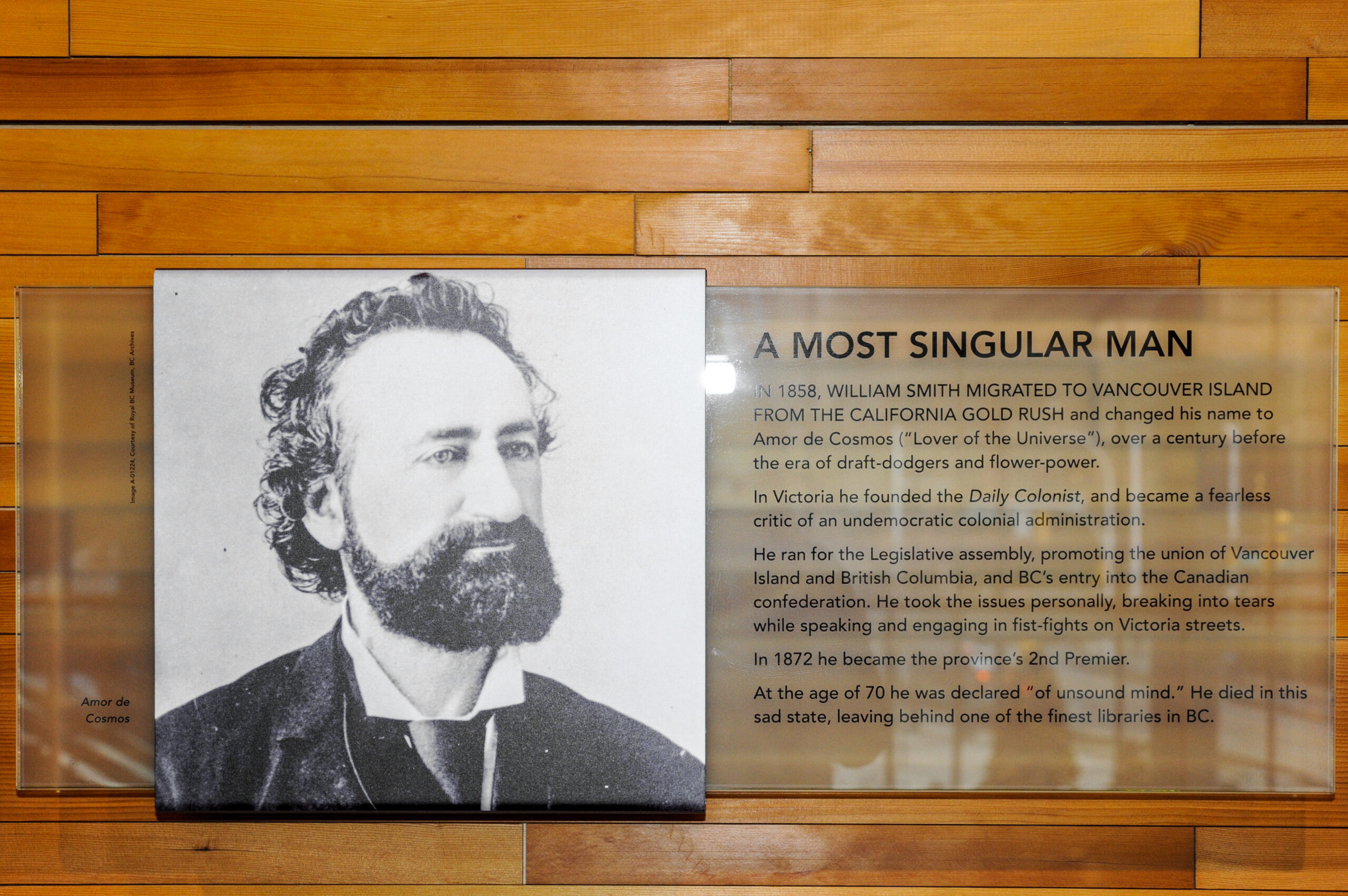 The plaque reads: In 1858, William Smith migrated to Vancouver Island from the California gold rush and changed his name to Amor de Cosmos (“Lover of the Universe,”) over a century before the era of draft-dodgers and flower-power. In Victoria, he founded the Daily Columnist and became a fearless critic of an undemocratic colonial administration. He ran for the Legislative Assembly, promoting the union of Vancouver Island and British Columbia, and BC's entry into the Canadian confederation. He took the issues personally, breaking into tears whilst speaking and engaging in fistfights on Victoria's streets. In 1872, he became the province's second premier. At the age of 70, he was declared “of unsound mind.” He died in this sad state, leaving behind one of the finest libraries in BC.