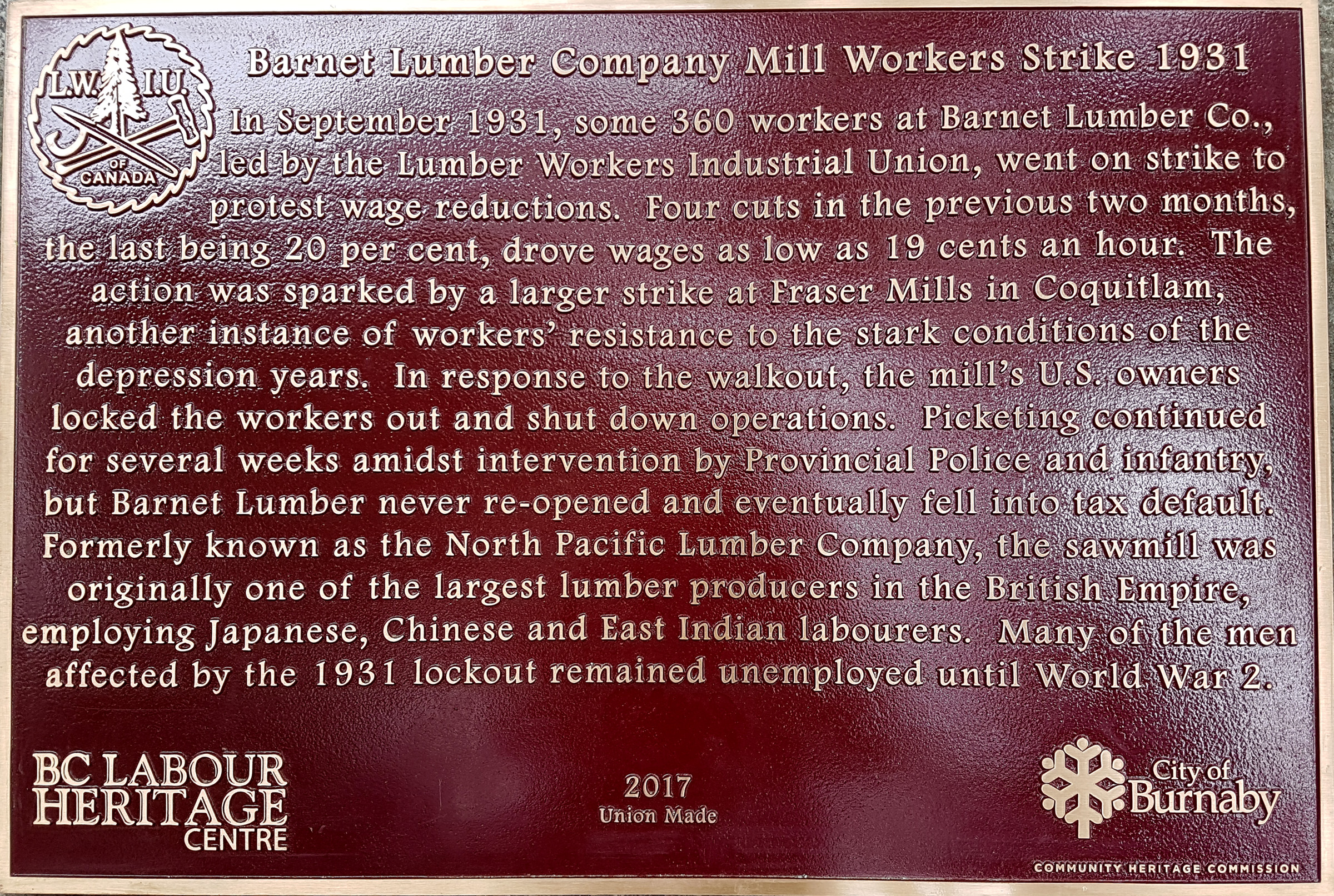 The plaque reads: In September 1931, some 360 workers at Barnet Lumber Co., led by the Lumber Workers Industrial Union, went on strike to protest wage reductions. Four cuts in the previous two months, the last being 20 per cent, drove wages as low as 19 cents an hour. The action was sparked by a larger strike at Fraser Mills in Coquitlam, another instance of workers’ resistance to the stark conditions of the depression years. In response to the walkout, the mill’s U.S. owners locked the workers out and shut down operations. Picketing continued for several weeks amidst intervention by Provincial Police and infantry, but Barnet Lumber never re-opened and eventually fell into tax default. Formerly known as the North Pacific Lumber Company, the sawmill was originally one of the largest lumber producers in the British Empire, employing Japanese, Chinese and East Indian labourers. Many of the men affected by the 1931 lockout remained unemployed until World War II. BC Labour Heritage Centre 2017 Union Made City of Burnaby Community Heritage Commission