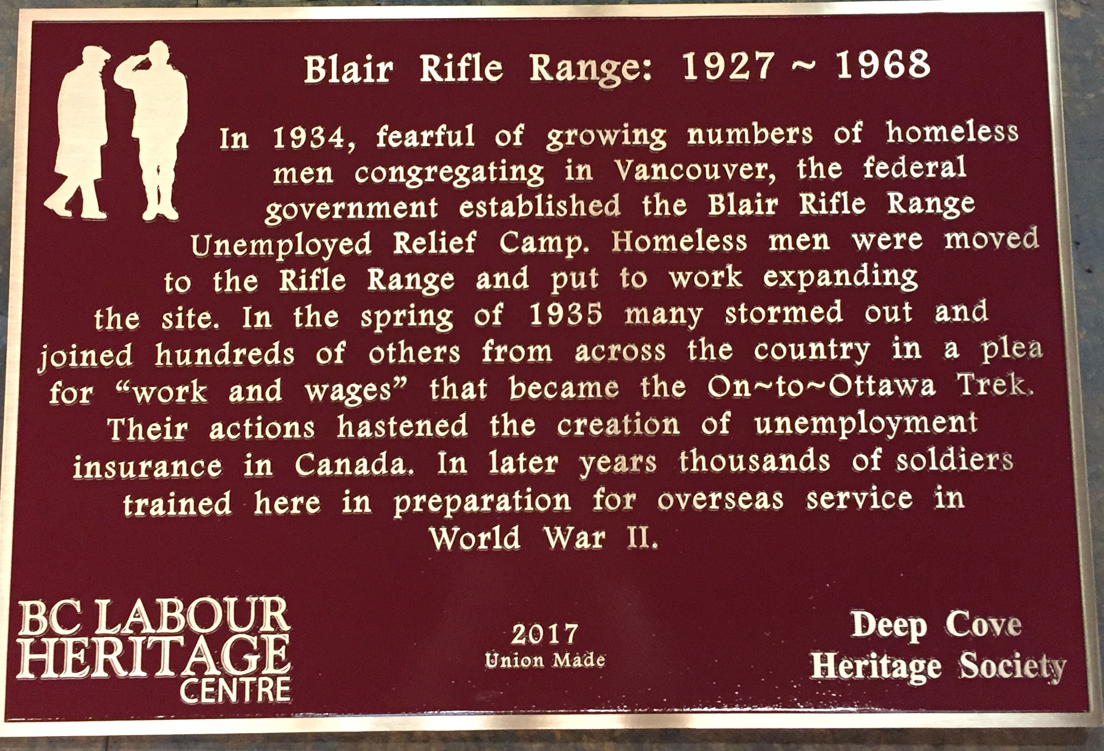 The plaque reads: In 1934, fearful of growing numbers of homeless men congregating in Vancouver, the federal government established the Blair Rifle Range Unemployed Relief Camp. Homeless men were moved to the Rifle Range and put to work expanding the site. In the spring of 1935 many stormed out and joined hundreds of others from across the country in a plea for “work and wages” that became the On-to-Ottawa Trek. Their actions hastened the creation of unemployment insurance in Canada. In later years thousands of soldiers trained here in preparation for overseas service in World War II. BC Labour Heritage Centre 2017 Union Made Deep Cove Heritage Society