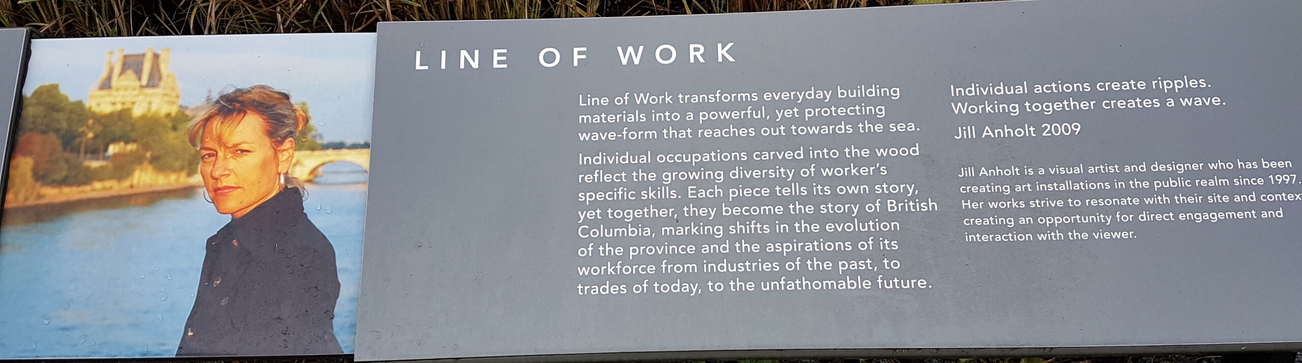 The plaque reads: Line of Work transforms everyday building materials into a powerful, yet protecting wave-form that reaches out towards the sea. Individual occupations carved into the wood reflect the growing diversity of worker’s specific skills. Each piece tells its own story, yet together, they become the story of British Columbia, marking shifts in the evolution of the province and the aspirations of its workforce from industries of the past, to trades of today, to the unfathomable future. “Individual actions create ripples. Working together creates a wave.” – Jill Anholt 2009 Jill Anholt is a visual artist and designer who has been creating art installations in the public realm since 1997. Her works strive to resonate with their site and context, creating an opportunity for direct engagement and interaction with the viewer.