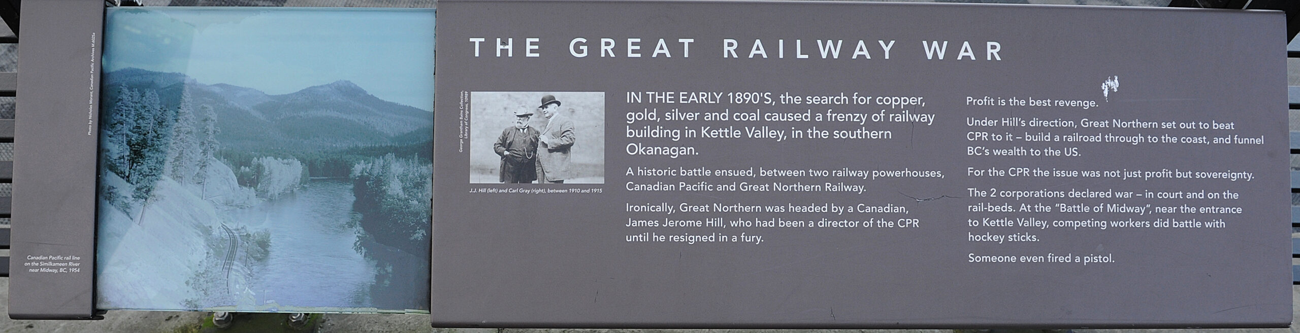 The plaque reads: IN THE EARLY 1890’s, the search for copper, gold, silver and coal caused a frenzy of railway building in Kettle Valley, in the southern Okanagan. A historic battle ensued, between two railway powerhouses, Canadian Pacific and Great Northern Railway. Ironically, Great Northern was headed by a Canadian, James Jerome Hill, who had been a director of the CPR until he resigned in a fury. Profit is the best revenge. Under Hill’s direction, Great Northern set out to beat CPR to it – build a railroad through to the coast, and funnel BC’s wealth to the US. For the CPR the issue was not just profit but sovereignty. The two corporations declared war – in court and on the rail-beds. At the “Battle of Midway”, near the entrance to Kettle Valley, competing workers did battle with hockey sticks. Someone even fired a pistol.