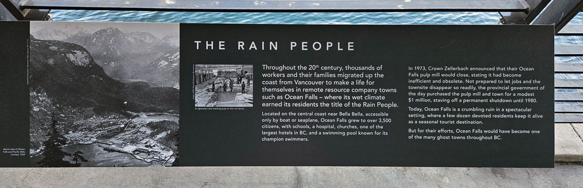 The plaque reads: Throughout the 20th century, thousands of workers and their families migrated up the coast from Vancouver to make a life for themselves in remote resource company towns such as Ocean Falls – where its wet climate earned its residents the title of the Rain People. Located on the central coast near Bella Bella, accessible only by boat or seaplane, Ocean Falls grew to over 3,500 citizens, with schools, a hospital, churches, one of the largest hotels in BC, and a swimming pool known for its champion swimmers. In 1973, Crown Zellerbach announced that their Ocean Falls pulp mill would close, stating it had become inefficient and obsolete. Not prepared to let jobs and the townsite disappear so readily, the provincial government of the day purchased the pulp mill and town for a modest $1 million, staving off a permanent shutdown until 1980. Today, Ocean Falls is a crumbling ruin in a spectacular setting, where a few dozen devoted residents keep it alive as a seasonal tourist destination. But for their efforts, Ocean Falls would have become one of the many ghost towns throughout BC.