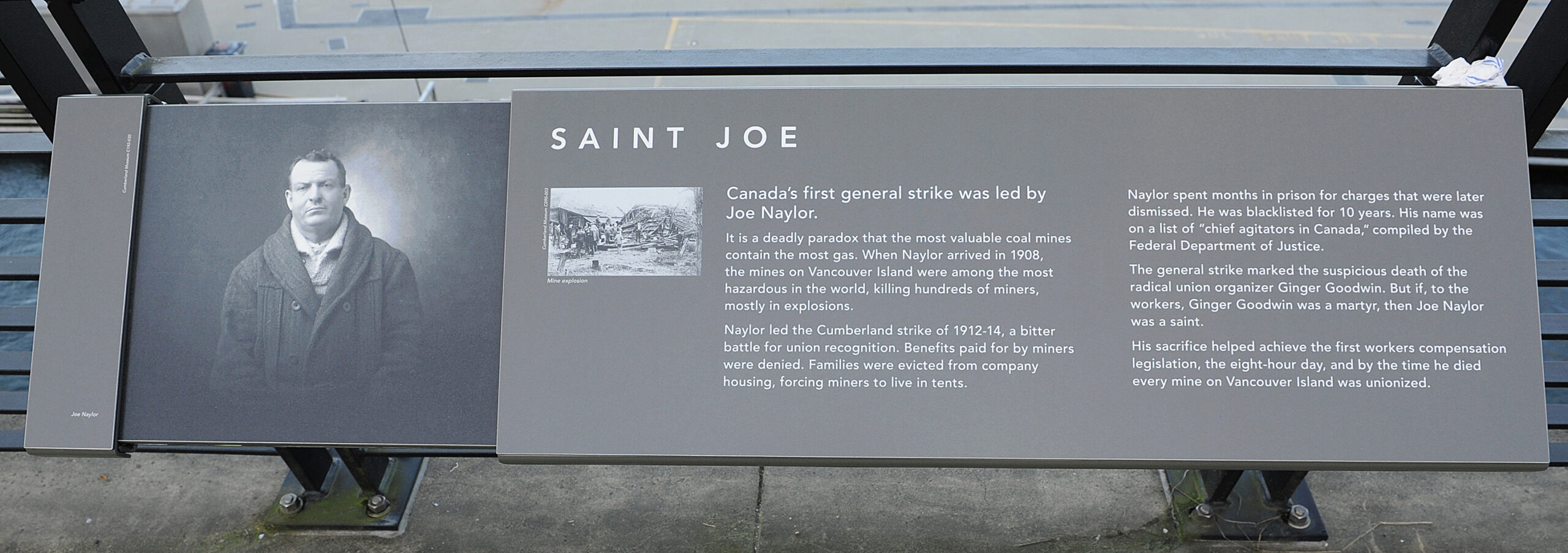 The plaque reads: Canada’s first general strike was led by Joe Naylor. It is a deadly paradox that the most valuable coal mines contain the most gas. When Naylor arrived in 1908, the mines on Vancouver Island were among the most hazardous in the world, killing hundreds of miners, mostly in explosions. Naylor led the Cumberland strike of 1912–14, a bitter battle for union recognition. Benefits paid for by miners were denied. Families were evicted from company housing, forcing miners to live in tents. Naylor spent months in prison for charges that were later dismissed. He was blacklisted for 10 years. His name was on a list of “chief agitators in Canada,” compiled by the Federal Department of Justice. The general strike marked the suspicious death of the radical union organizer Ginger Goodwin. But if, to the workers, Ginger Goodwin was a martyr, then Joe Naylor was a saint. His sacrifice helped achieve the first workers compensation legislation, the eight-hour day, and by the time he died every mine on Vancouver Island was unionized.