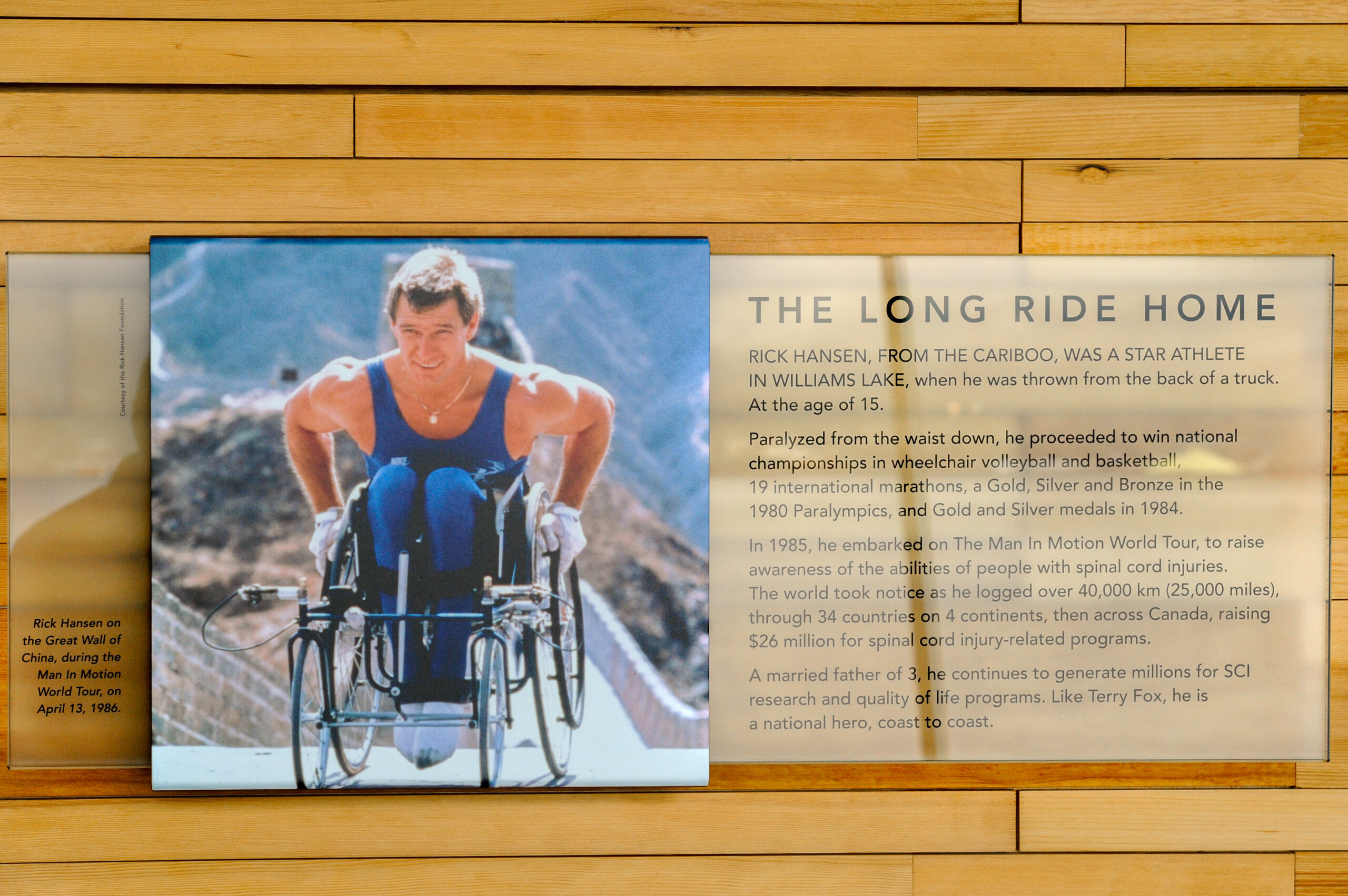The plaque reads: Rick Hansen, from the Cariboo, was a star athlete in Williams Lake, when he was thrown from the back of a truck at the age of 15. Paralyzed from the waist down, he proceeded to win national championships in wheelchair volleyball and basketball, 19 international marathons, a Gold, Silver, and Bronze in the 1980 Paralympics, and Gold and Silver medals in 1984. In 1985, he embarked on The Man in Motion World Tour to raise awareness of the abilities of people with spinal cord injuries. The world took notice as he logged over 40,000 km (25,000 miles) through 34 countries on four continents, then across Canada, raising $26 million for spinal cord injury-related programs. A married father of three, he continues to generate millions for SCI research and quality of life programs. Like Terry Fox, he is a national hero, coast to coast.