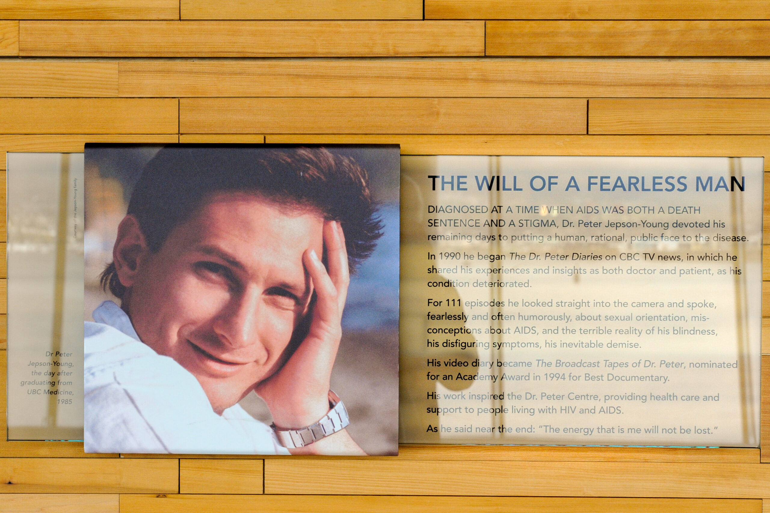 The plaque reads: Diagnosed at a time when AIDS was both a death sentence and a stigma, Dr. Peter Jepson-Young devoted his remaining days to putting a human, rational, public face to the disease. In 1990, he began The Dr. Peter Diaries on CBC TV News, in which he shared his experiences and insights, both as a doctor and patient, as his condition deteriorated. For 111 episodes, he looked straight into the camera and spoke, fearlessly and often humorously, about sexual orientation, misconceptions about AIDS, and the terrible reality of his blindness, his disfiguring symptoms, his inevitable demise. His video diary became The Broadcast Tapes of Dr. Peter, nominated for an Academy Award in 1994 for Best Documentary. His work inspired the Dr. Peter Center, providing healthcare and support to people living with HIV and AIDS. As he said near the end: “The energy that is me will not be lost.”