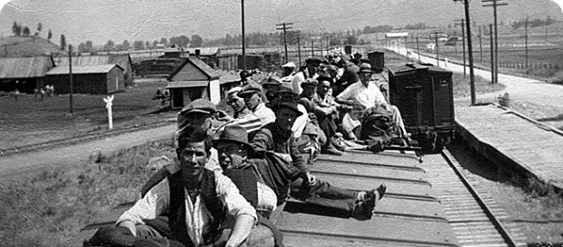 Black and white photo of a group of men sitting on top of a train