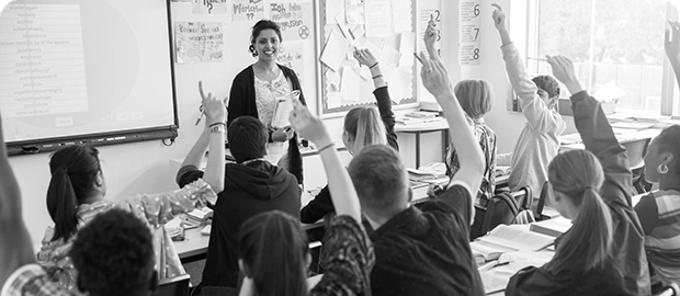 Teacher in front of a classroom full of students with raised hands