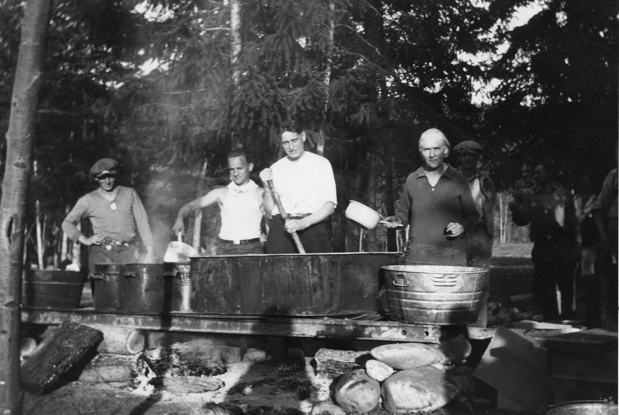 5 men cooking in a bathtub outside in a labour camp