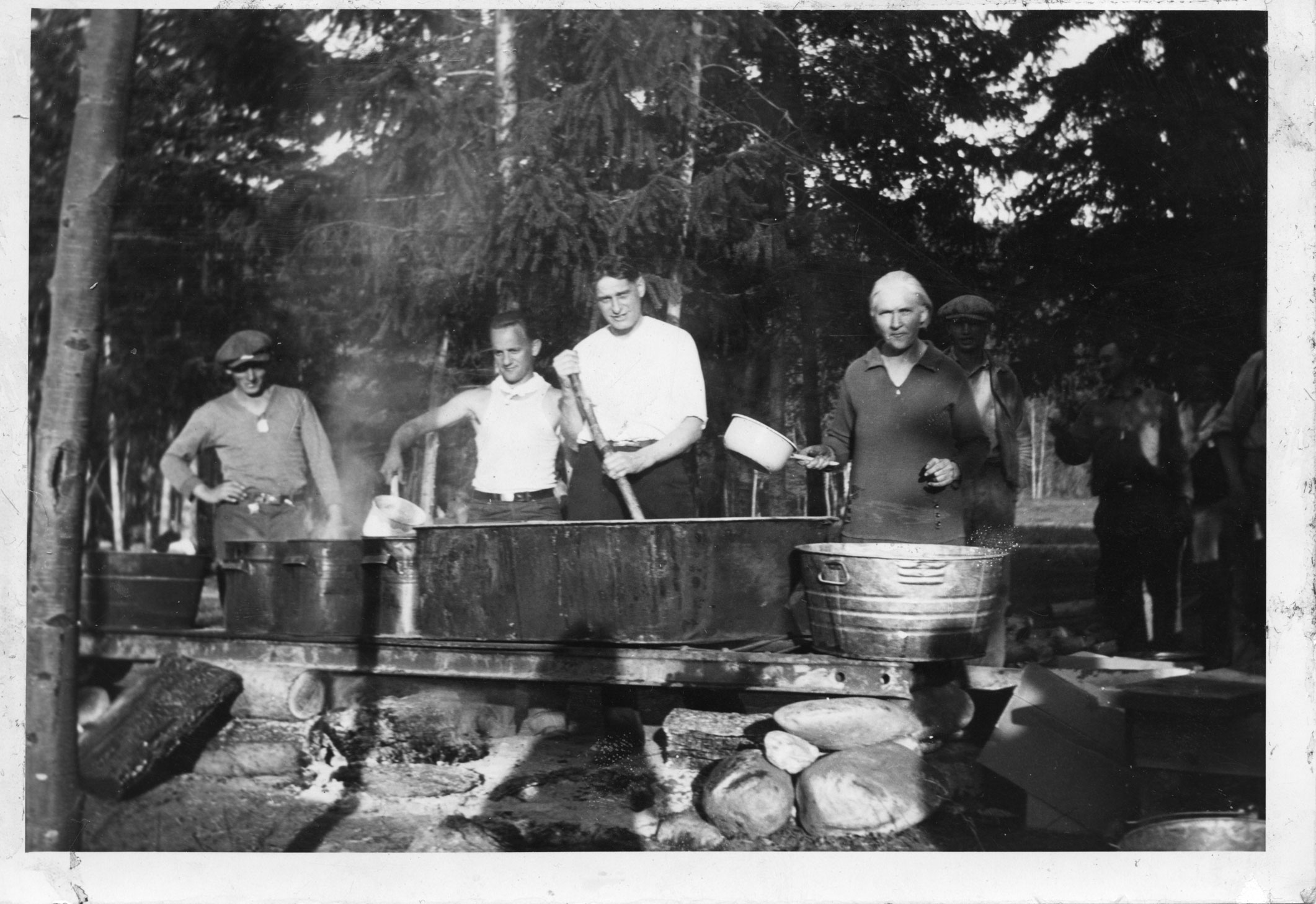 5 men cooking in a bathtub outside in a labour camp