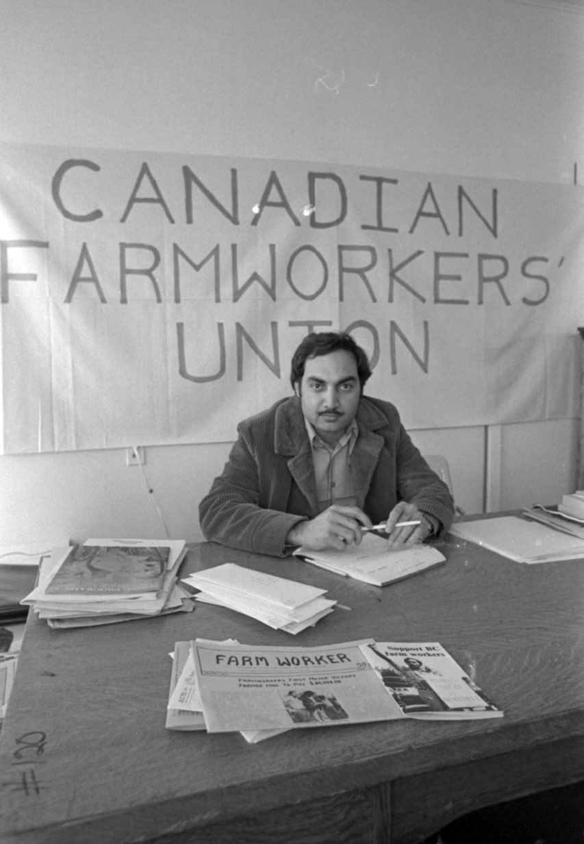 Person sitting at a desk with a banner behind the that reads: "Canadian Farmers Union"