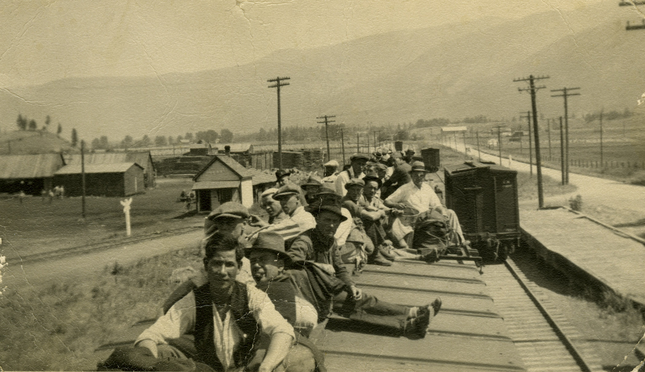 Black and white photo of a group of men sitting on top of a train