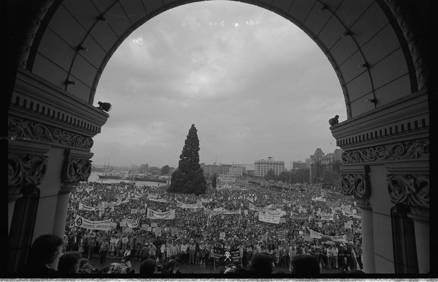 Black and white photo on the steps of the legislature overlooking a huge crowed of protesters.