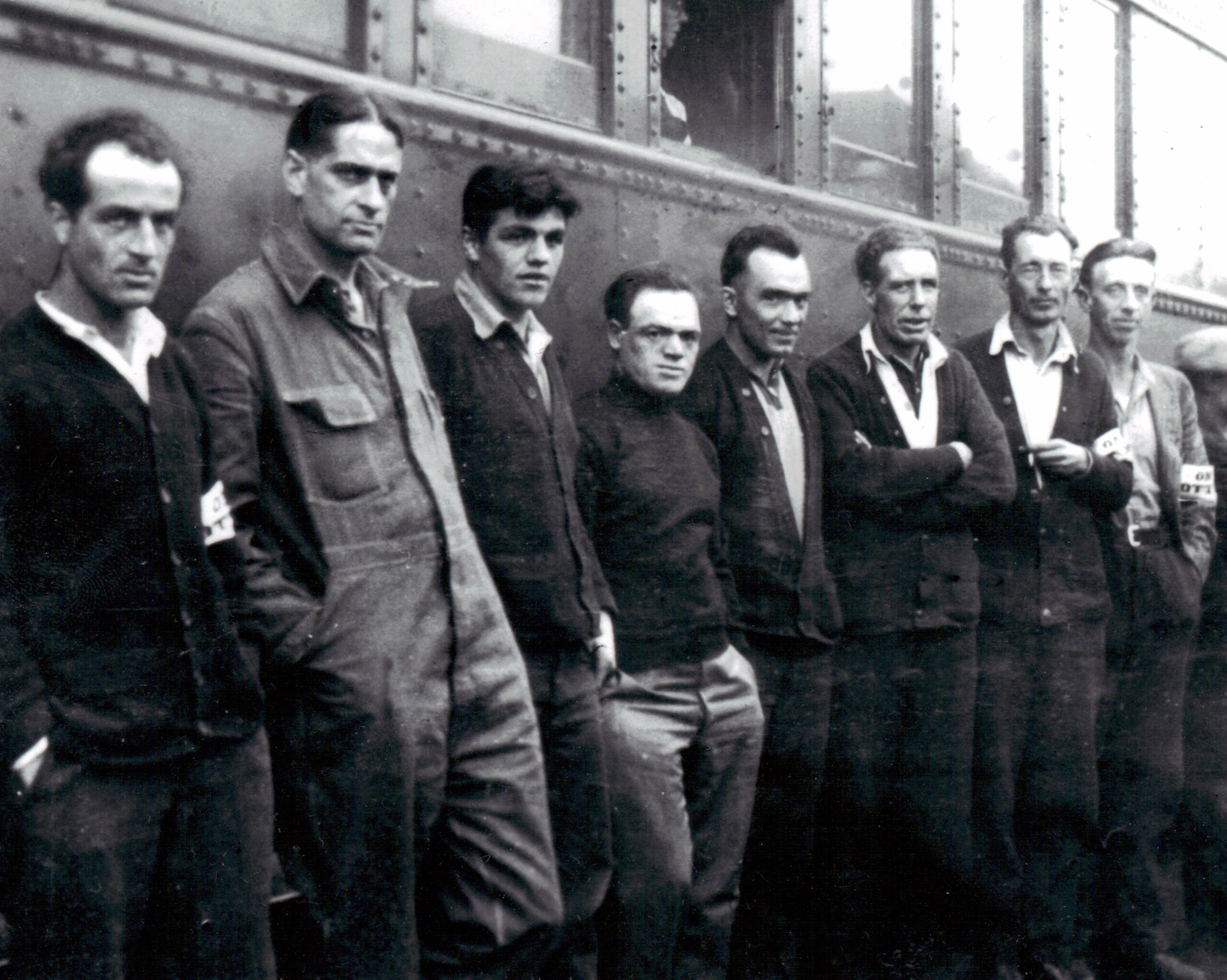 Black and white photo of a group of men posing against a train cart